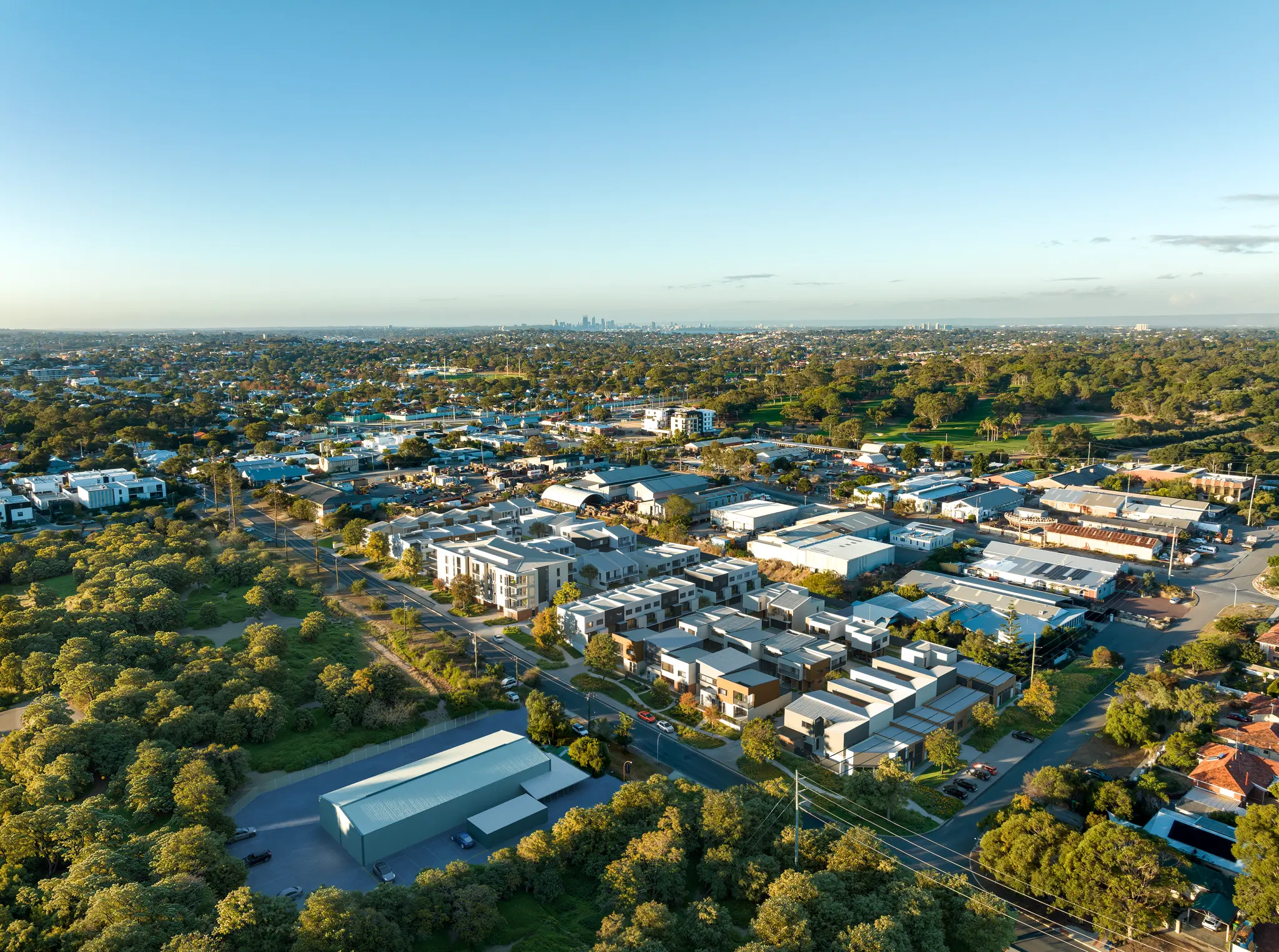 High-resolution aerial architectural photomontage of a contemporary residential precinct integrated into an established urban and parkland setting